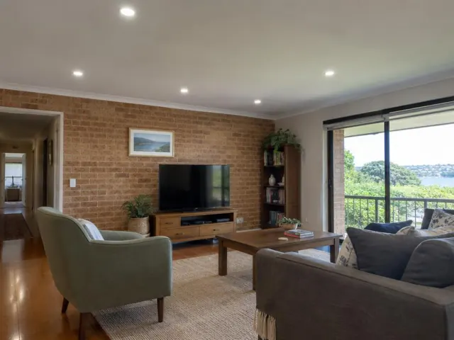 Living room with several recessed ceiling downlights, brick wall, sofa, TV and balcony view in Green Point