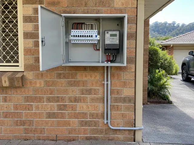 Open outdoor electrical switchboard on a brick house wall with meter and conduit in Kincumber